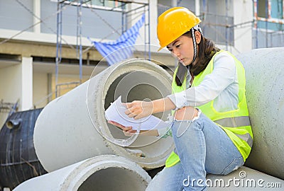 Woman engineers looking blueprint at construction site Stock Photo