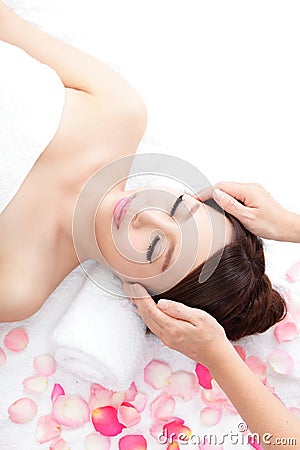 Woman enjoy receiving face massage at spa with roses Stock Photo