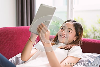 Woman enjoy relax at home with tablet on red sofa. Relax and Holiday concept Stock Photo