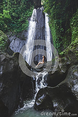 Woman enjoying near hidden in jungle cascade waterfall Dusun Kuning in Bali Stock Photo