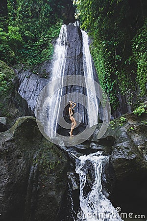 Woman enjoying near hidden in jungle cascade waterfall Dusun Kuning in Bali Stock Photo