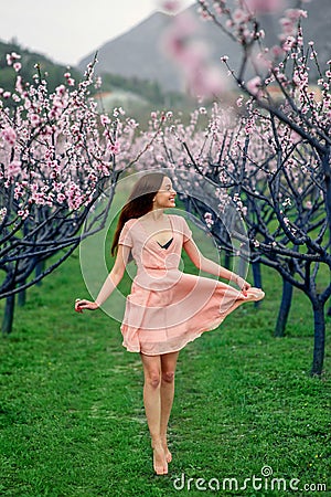 Woman enjoying spring in the green field with blooming trees Stock Photo