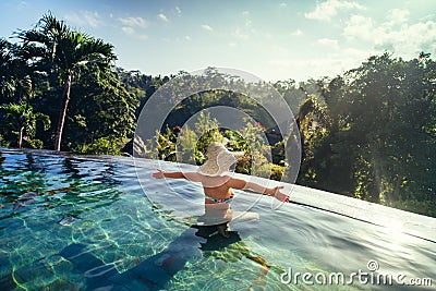 woman enjoying the sun at infinity summer swimming pool at luxurious resort Stock Photo