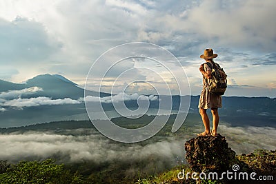 Woman enjoying sunrise from a top of mountain Batur, Bali, Indonesia Stock Photo