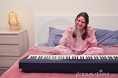 A woman enjoys the success of playing the piano in the home bedroom, the exultation of a musician Stock Photo