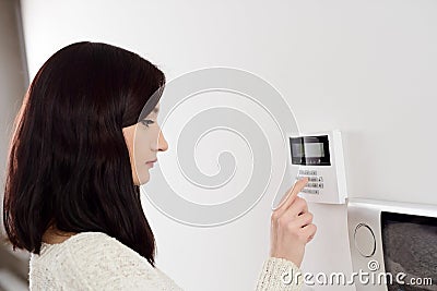 Woman entering code on keypad of home security alarm Stock Photo