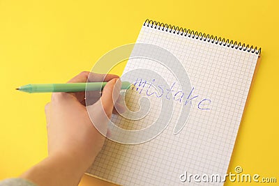 Woman erasing word Mistake written with erasable pen in notepad on yellow background, above view Stock Photo