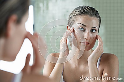 Woman Examining Herself In Front Of Mirror Stock Photo