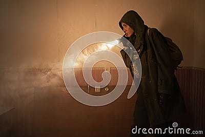 Woman explorer with flashlight inside corridor or tunnel of ruined industrial building factory, horror and creepy Stock Photo