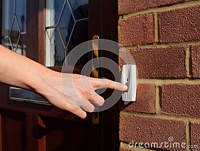 Woman extends her hand to ring doorbell Stock Photo
