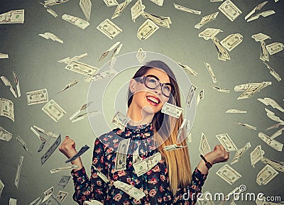 Woman exults pumping fists ecstatic celebrates success under money rain falling down dollar bills banknotes Stock Photo