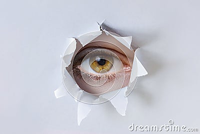 Woman eye observes through a hole in the paper Stock Photo