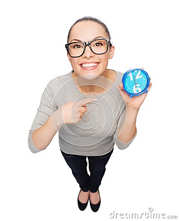 Woman in eyeglasses pointing finger to blue clock Stock Photo