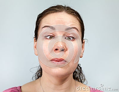 Woman with eyes slanted to her nose, crossed eyes, craziness, portrait on grey background, emotions series Stock Photo
