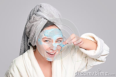 Woman with facial clay mask at spa salon or at home, skincare theme. Girl removes alginate cosmetic mask. Face mask, spa Stock Photo
