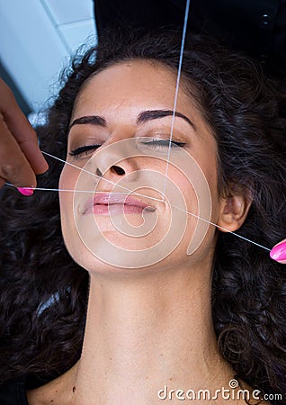 Woman on facial hair removal threading procedure Stock Photo