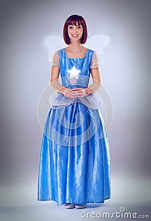 Woman, fairy godmother and smile in studio portrait with wand, wings and dress for magic by background. Person, fantasy Stock Photo