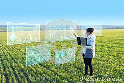 A woman farmer selects on a virtual screen the parameters that control the growth of the crop and analyzes the data using artifici Stock Photo