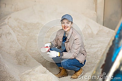 Woman farmer squatting at heap of corn flour Stock Photo