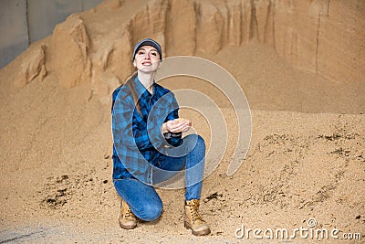 Woman farmer squatting at heap of soybean husk Stock Photo