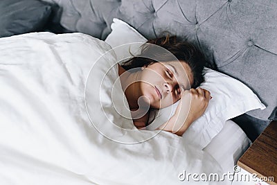 Young woman fast asleep sleeping in her bed on white bed linen Stock Photo
