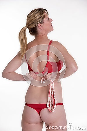 Woman fastening her red bra holding a tape measure Stock Photo