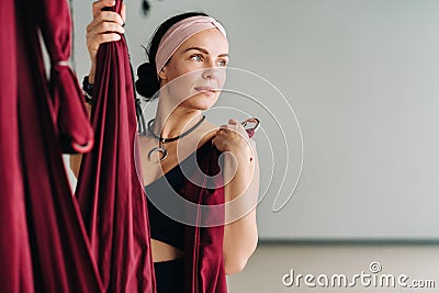 A woman fastens a hook from a hanging hammock for yoga in the gym Stock Photo