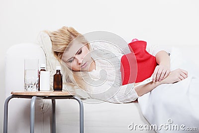 Woman feeling stomach cramps lying on cofa Stock Photo