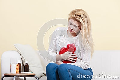 Woman feeling stomach cramps sitting on cofa Stock Photo