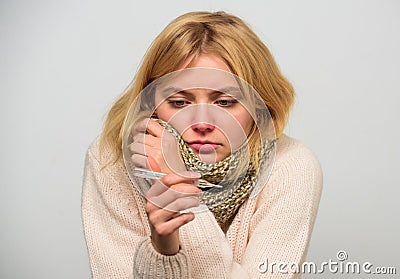 Woman feels badly ill sneezing. Girl in scarf hold thermometer and tissue close up. Measure temperature. High Stock Photo