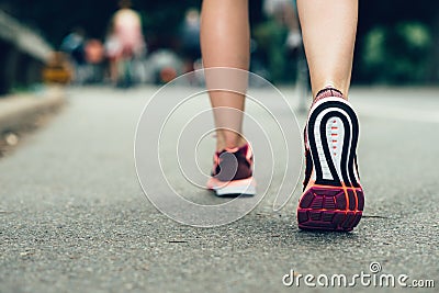 Woman feet close-up wearing sneakers during marathon run on asphalt city road Stock Photo