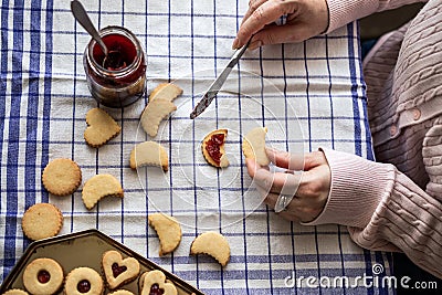 Woman filling homemade cookies with red currant jam Stock Photo