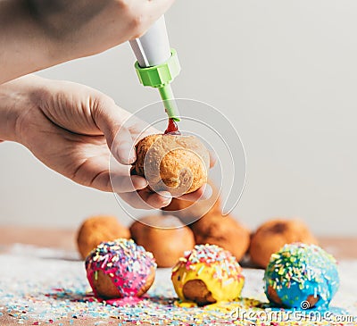 Woman filling homemade doughnut with rose jam Stock Photo