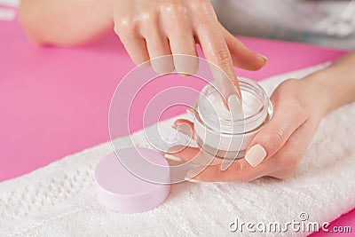 Woman finger touching open cream for hands on white towel Stock Photo