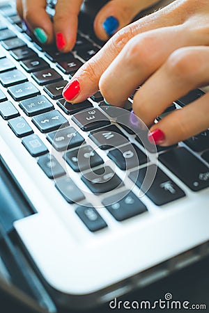 Home office or online shopping: Woman fingers with colorful nails are typing on a notebook keyboard Stock Photo