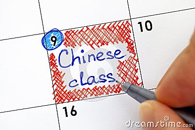 Woman fingers with pen writing reminder Chinese Class in calendar Stock Photo