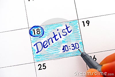 Woman fingers with pen writing reminder Dentist 10-30 in calendar Stock Photo