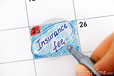 Woman fingers with pen writing reminder Insurance Fee in calendar. Stock Photo