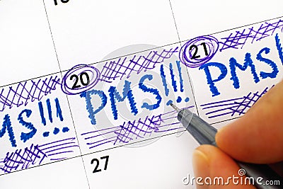 Woman fingers with pen writing reminder PMS in calendar. Stock Photo