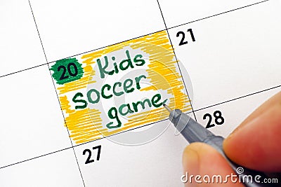 Woman fingers writing reminder Kids Soccer Game in calendar Stock Photo