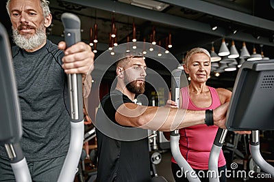 Woman first time at gym, trainer helping to set up equipment Stock Photo