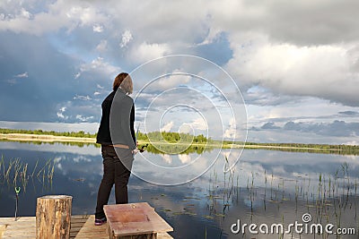 Woman fishing on wooden bridge in Seliger lake estuary Stock Photo