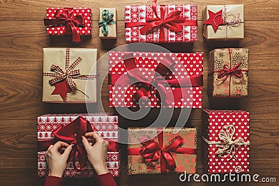 Woman fixing a bow on beautifuly wrapped vintage christmas presents on wooden background Stock Photo