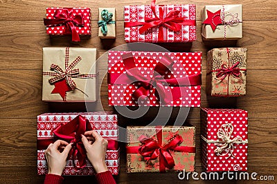 Woman fixing a bow on beautifuly wrapped vintage christmas presents on wooden background Stock Photo