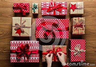 Woman fixing a bow on beautifuly wrapped vintage christmas presents on wooden background Stock Photo