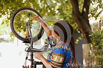 Woman fixing damaged bicycle wheel Stock Photo
