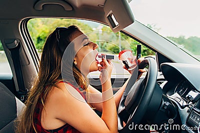 Woman fixing her lipstick in a car. Reckless drivier Stock Photo