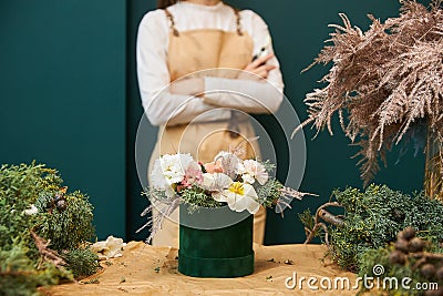 A woman florist ready bouquet in a beautiful green corduroy corduroy box, an empty place for text Stock Photo