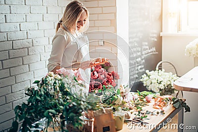 Woman florist taking pictures of flowers with mobile phone Stock Photo