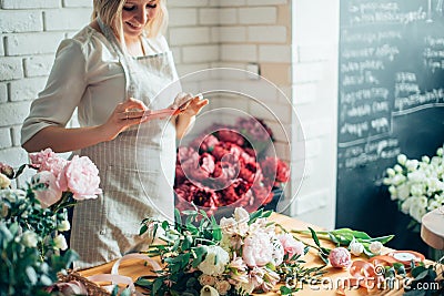 Woman florist taking pictures of flowers with mobile phone Stock Photo